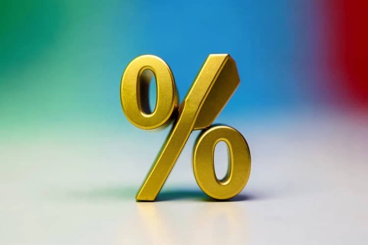 Símbolo de porcentagem (%) em dourado sobre um fundo escuro, indicando taxa.