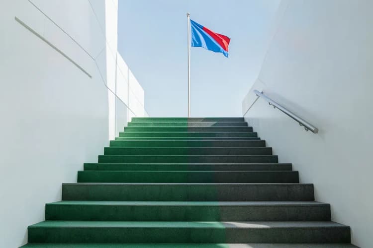 Uma série de degraus levando a um topo com uma bandeira, simbolizando as etapas de um processo.