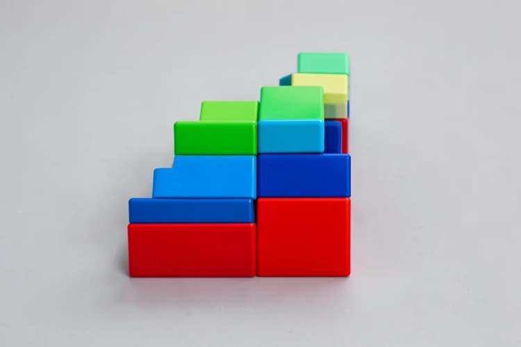 Um conjunto de blocos de construção coloridos sendo organizados em uma escada ascendente.