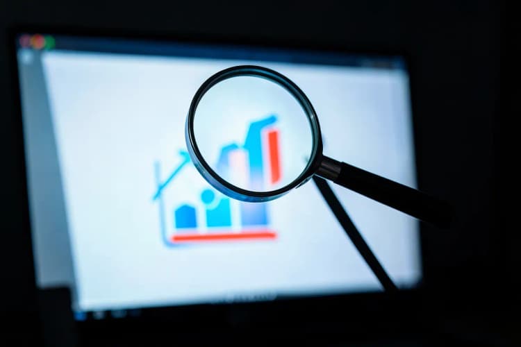 Uma lupa focando em um ícone de gráfico em uma tela de computador, representando a análise de dados de vendas online.