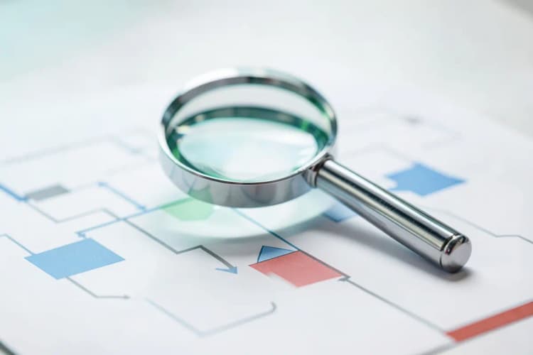 Uma lupa examinando um diagrama de fluxo com caixas e setas, representando análise de processo.